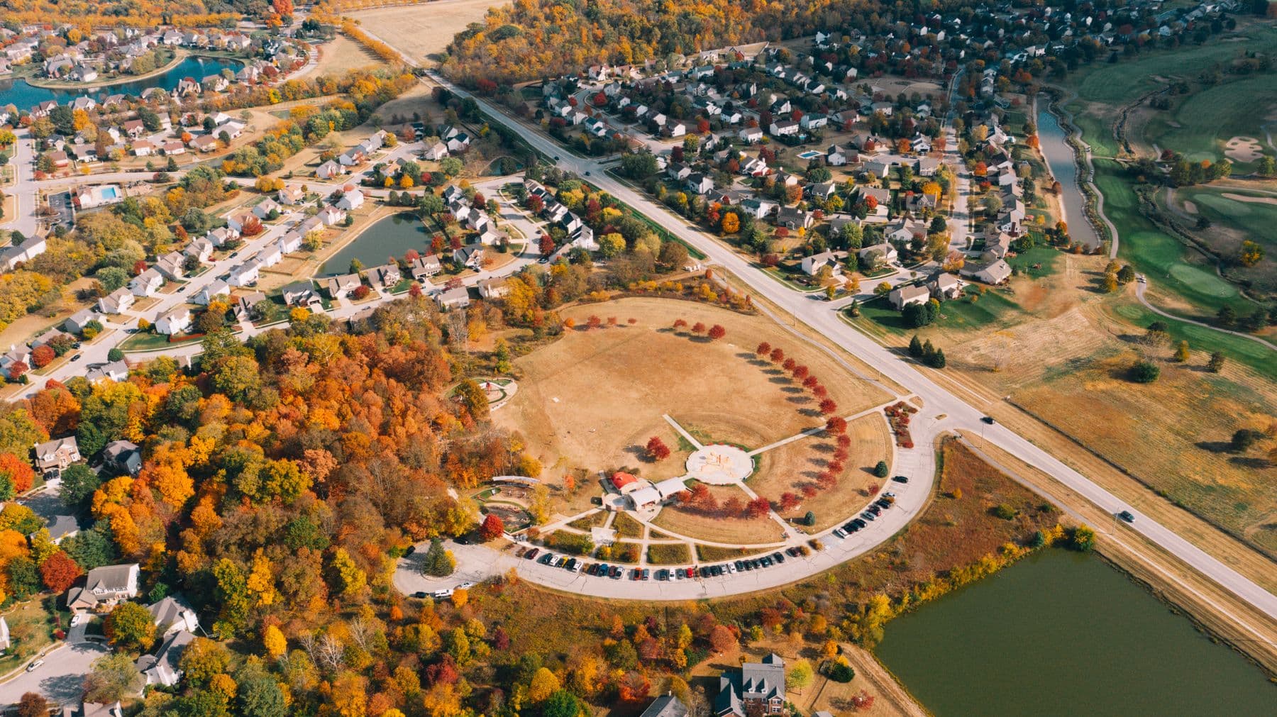 Aerial view of a suburban neighbourhood in autumn, with houses, pools, and tree-lined streets