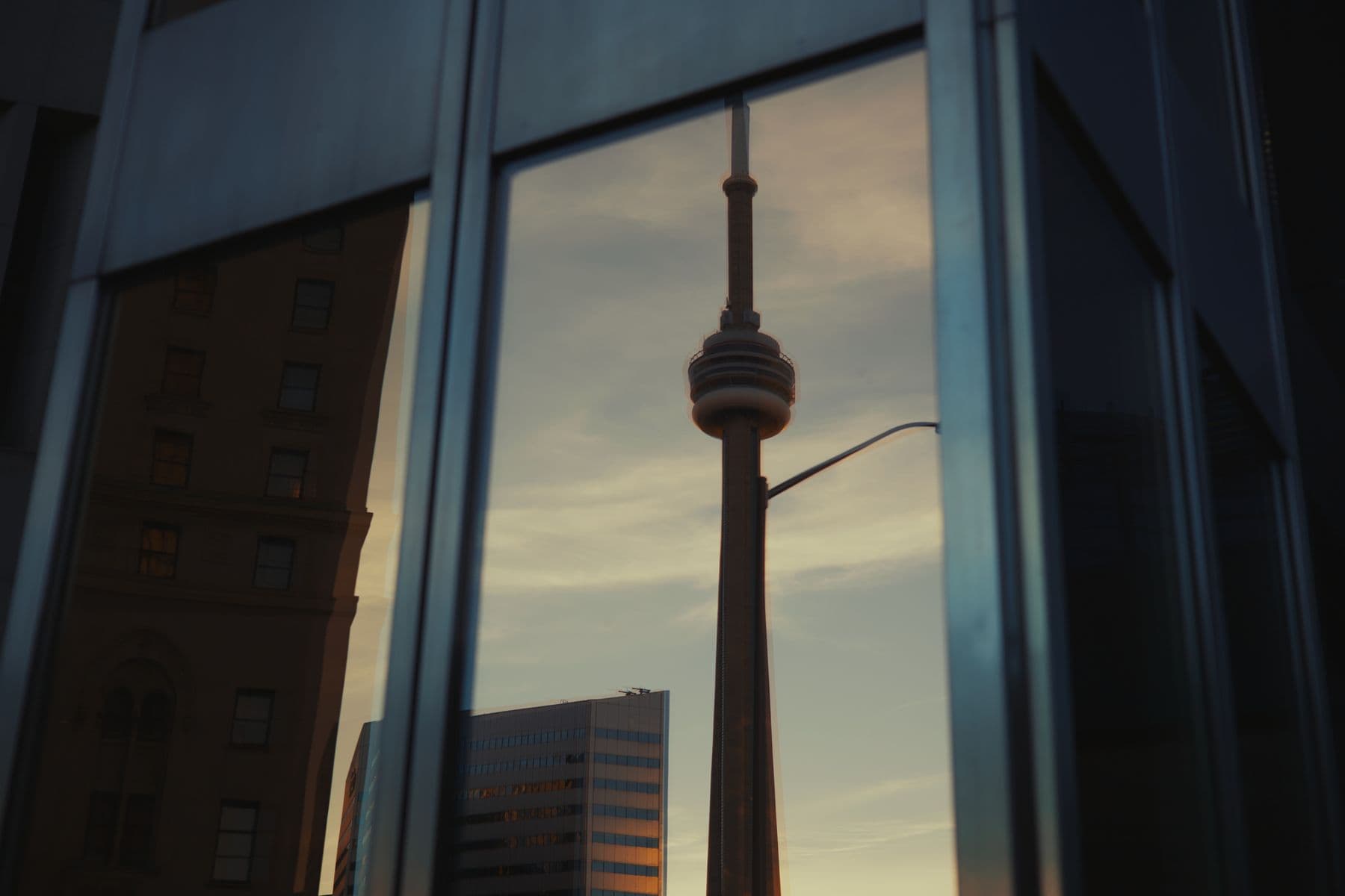 The CN Tower reflected in the glass windows of a Toronto building